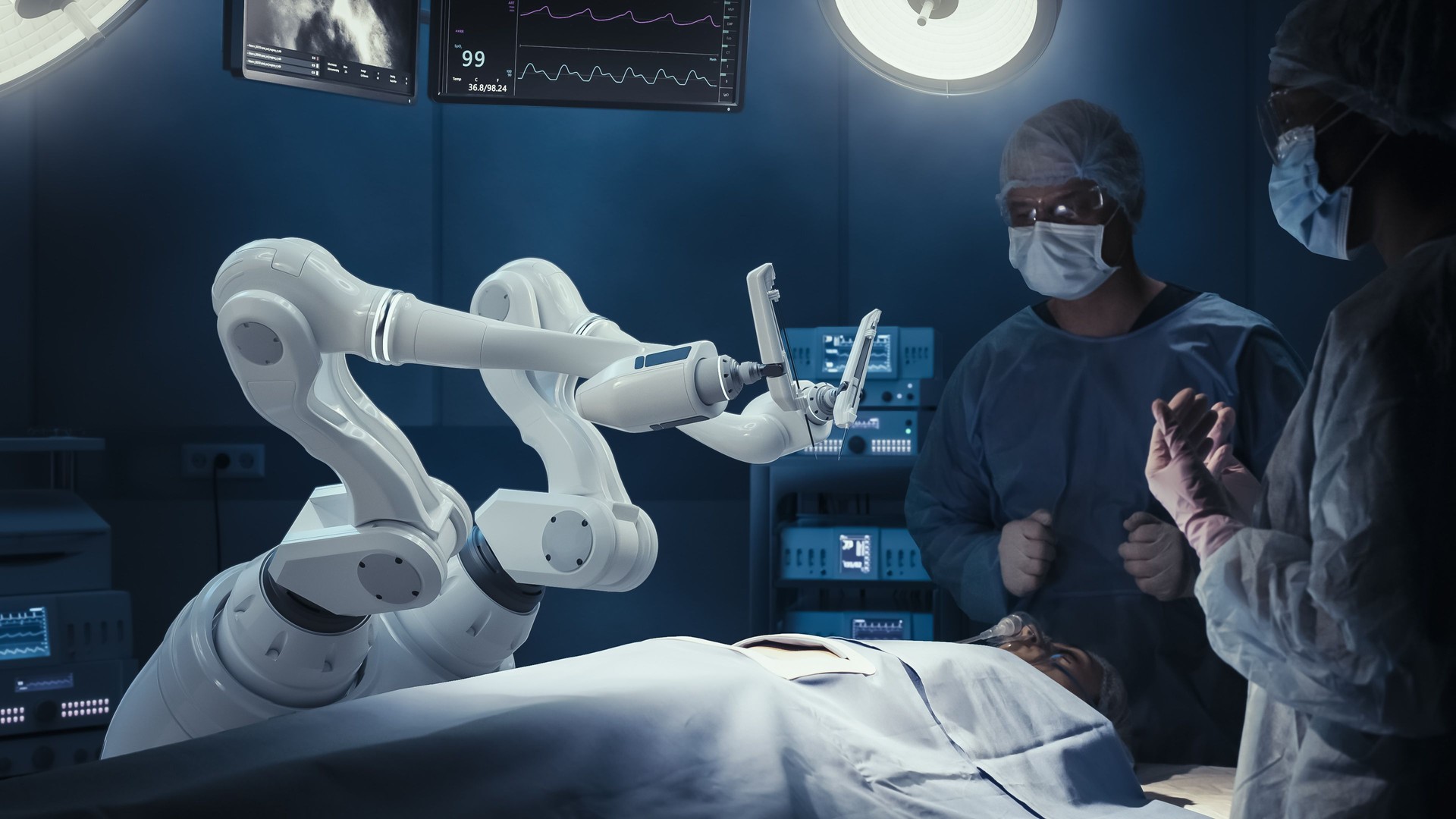 Two Surgeons Observing High-Precision Programmable Automated Robot Arms Operating Patient In Futuristic Hospital. Robotic Limbs Performing Advanced Nanosurgery, Doctors Looking At Vitals On Monitor
